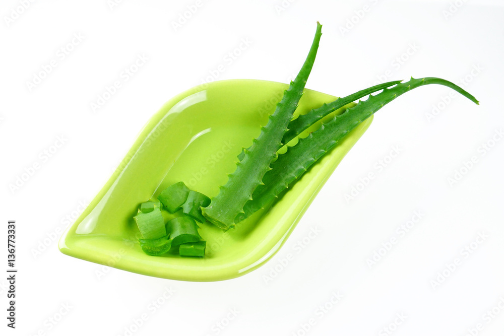 The leaves and pieces sliced of aloe vera on a beautiful green platter original form isolated on whi