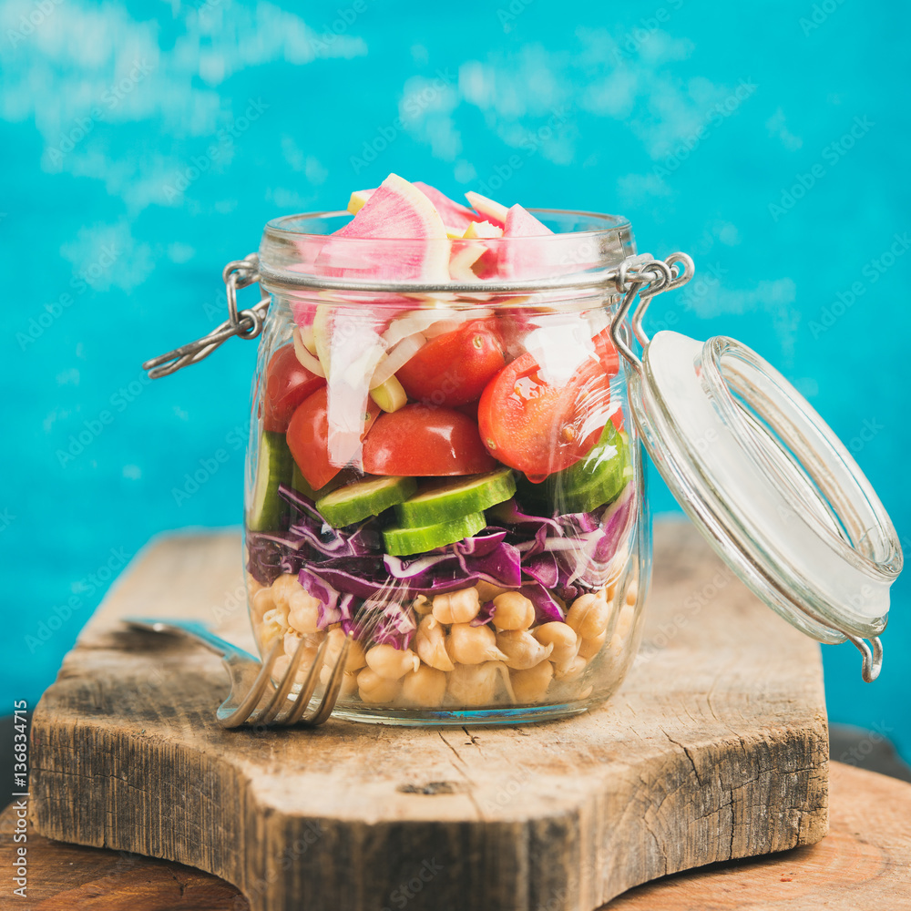 Healthy take-away lunch jar. Vegetable and chickpea sprout vegan salad in jar on wooden board, brigh