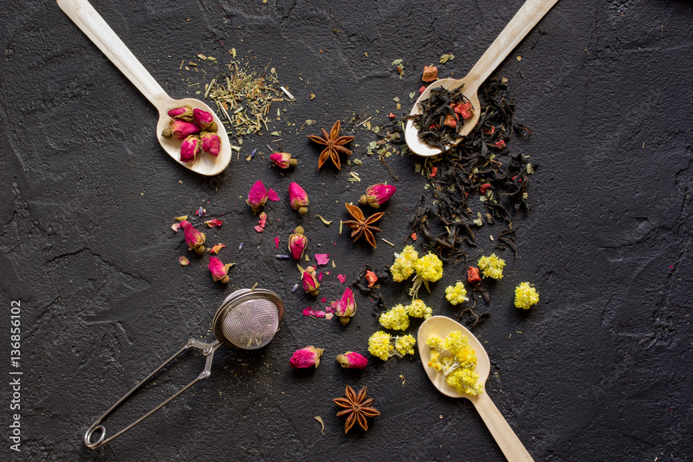 Spoons with herbs on dark background top view