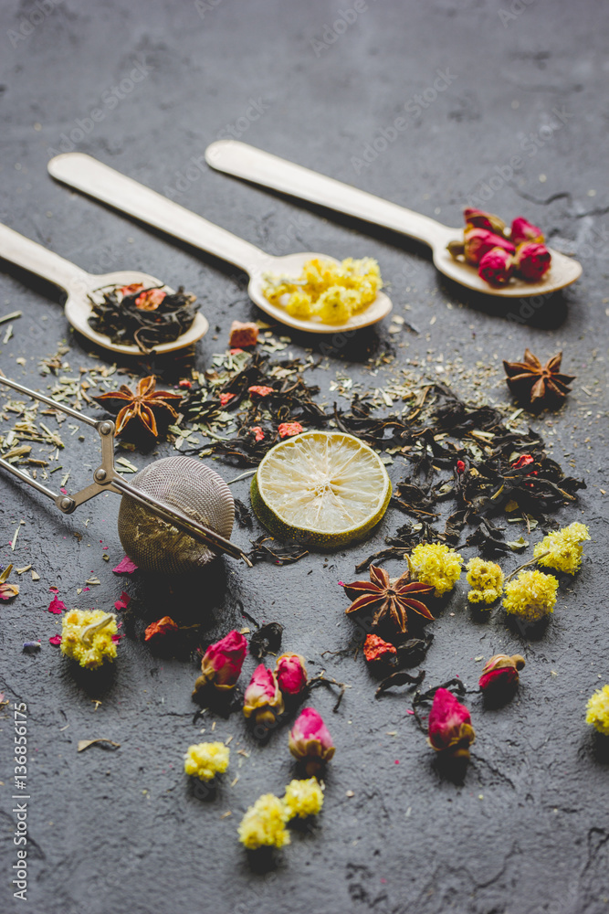 Spoons with herbs on dark stone background