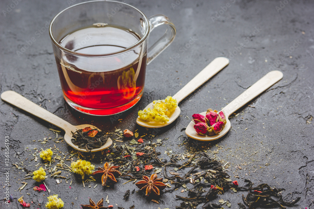 Teacup and herbs on dark stone background