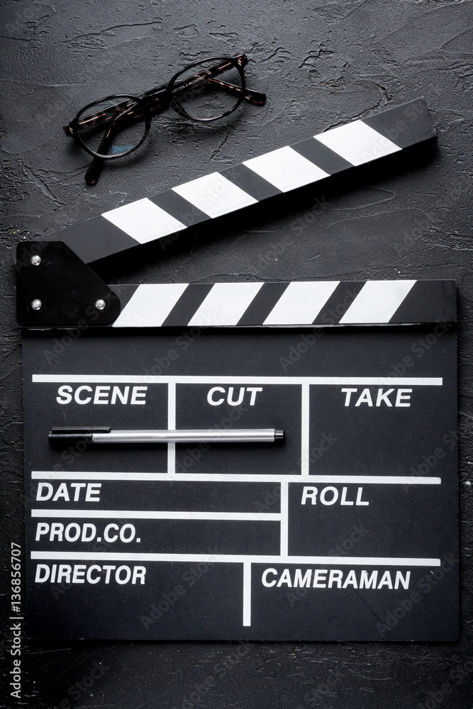 Screenwriter desktop with movie clapper board dark background top view