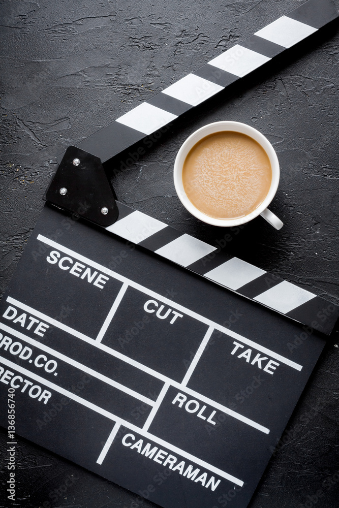 Screenwriter desktop with movie clapper board dark background top view