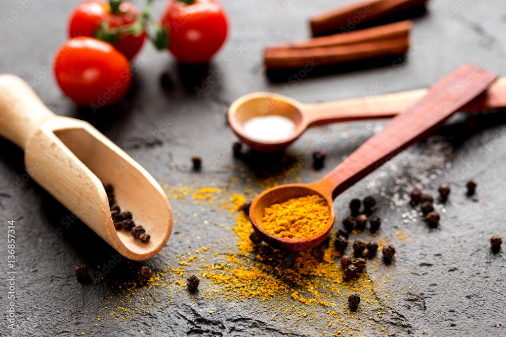 spices in wooden spoon on dark background