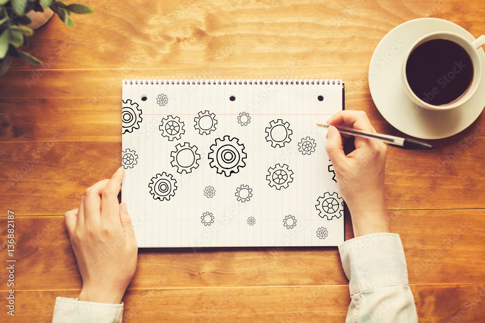 Gears with a person holding a pen