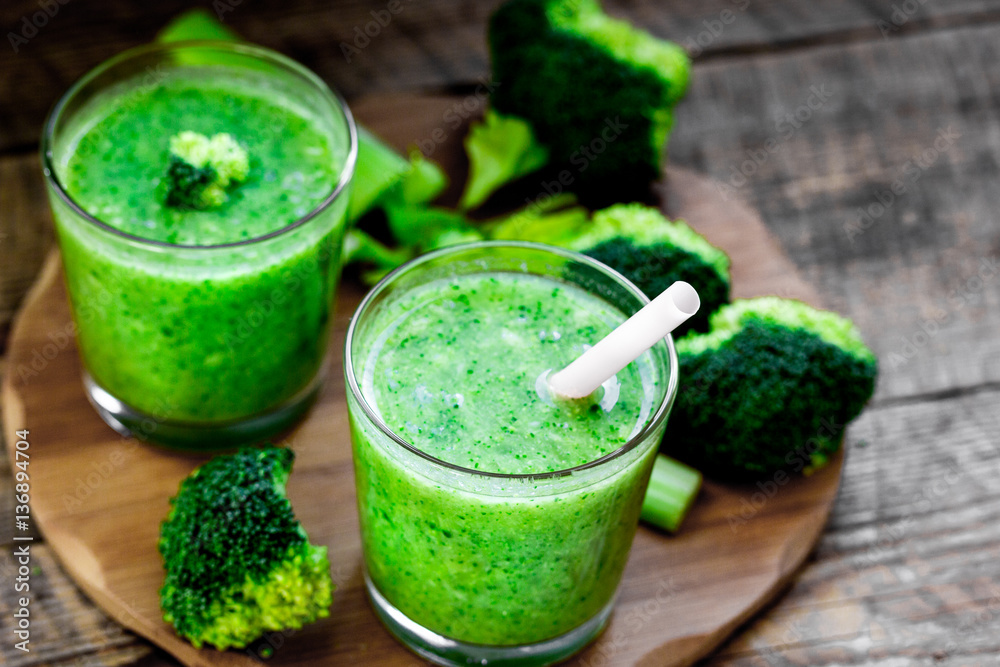 Green vegetable smoothie in glass at wooden background