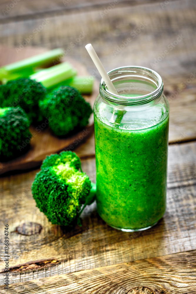 Green vegetable smoothie in glass at wooden background