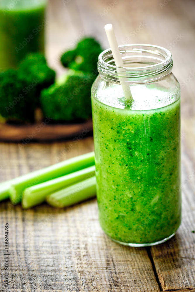 Green vegetable smoothie in glass at wooden background