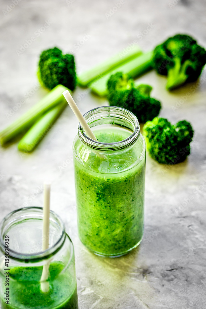 Green vegetable smoothie in glass at gray background