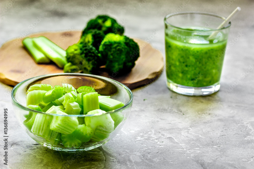 Green vegetable smoothie in glass at gray background