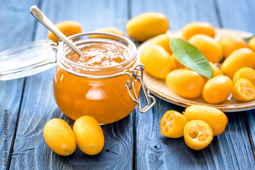 kumquat on plate and jam in jar at wooden table