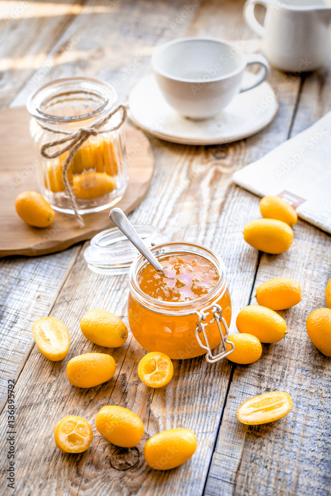 kumquat on plate and jam in jar at wooden table