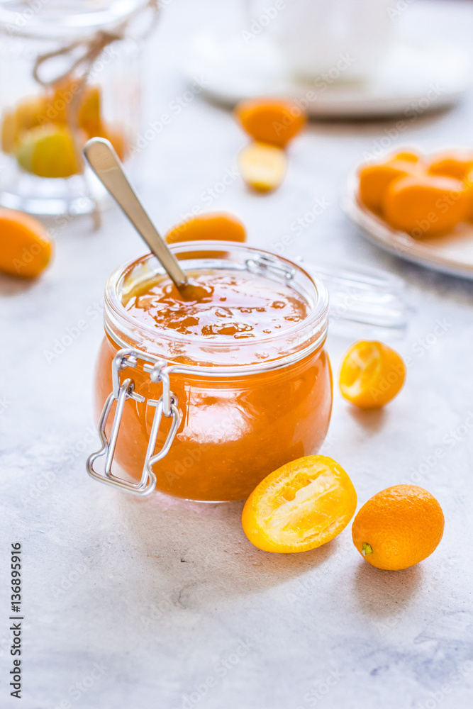 kumquat on plate and jam in jar at gray background