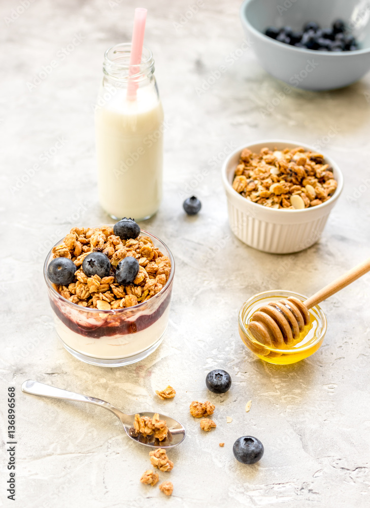 Morning granola in glass with yogurt, honey and milk on white desk