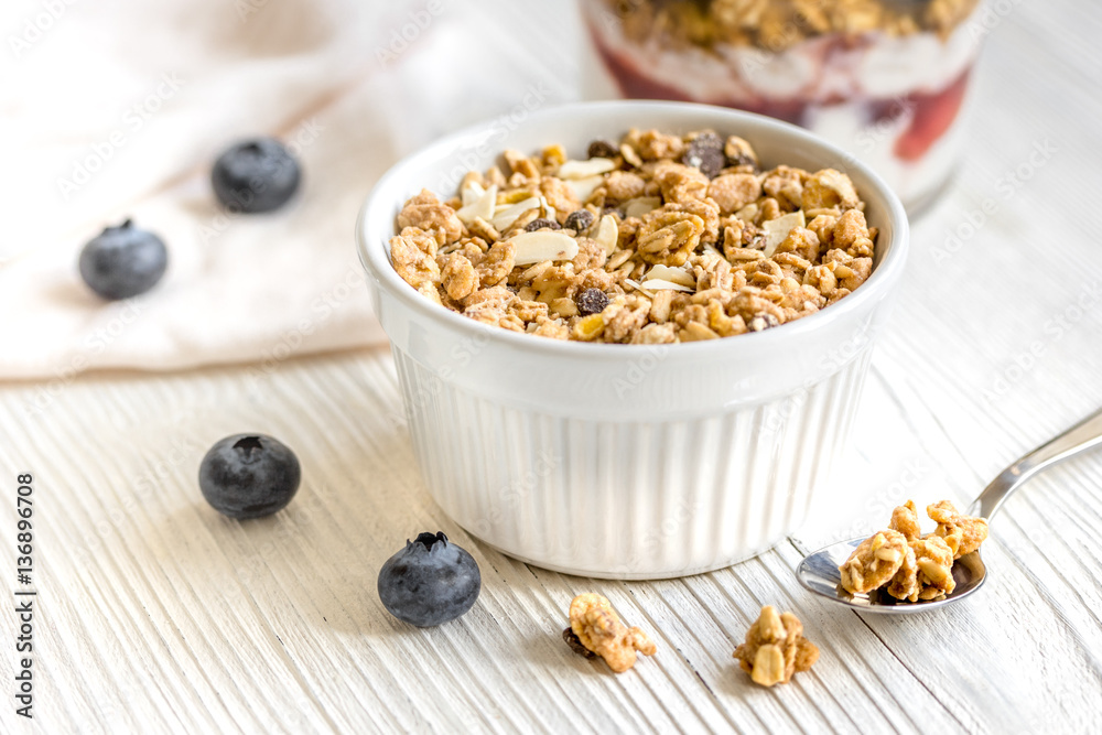 Homemade fitness granola with yoghurt and berries on white kitchen background