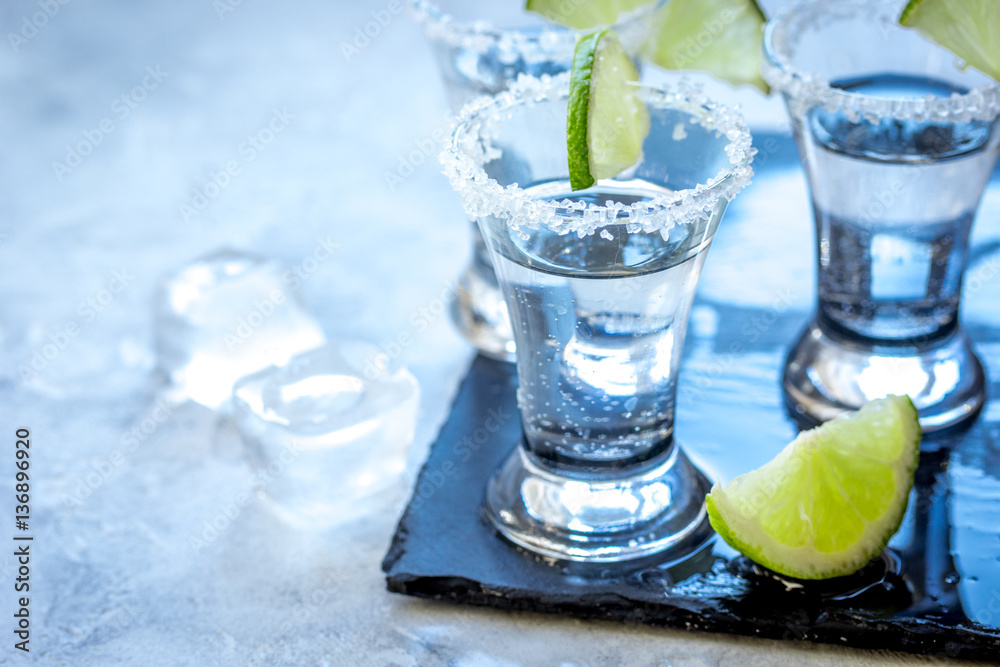 Silver tequila shots with lime and salt on gray stone background