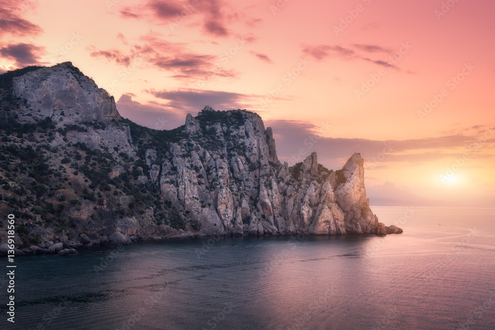 Mountains against colorful cloudy sky at sunset. Landscape with mountains, sea, red sky and yellow s