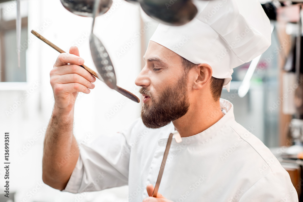 Chef cook tasting food with wooden spoon at the restaurant kitchen