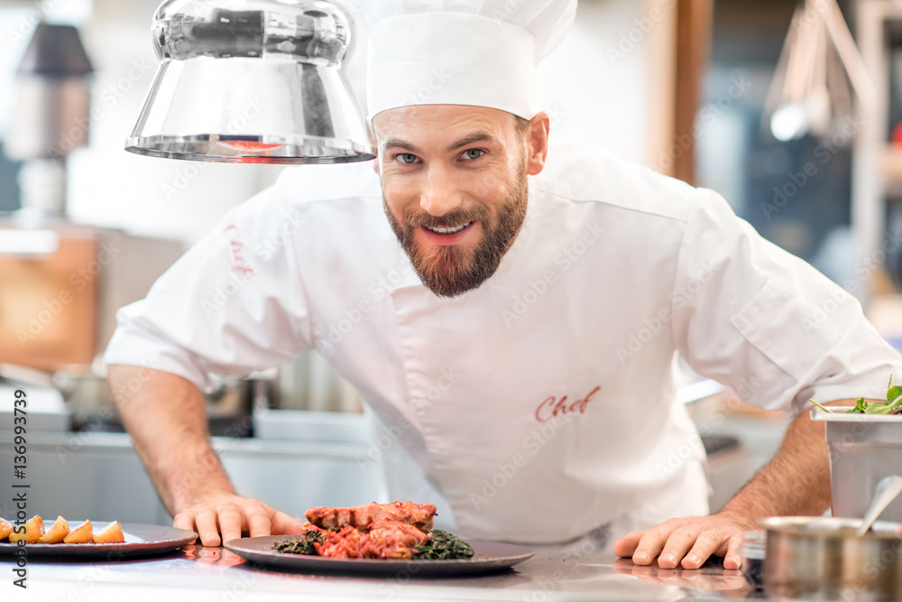 Portrait of chef cook in uniform with prepaired delicious dish at the restaurant kitchen