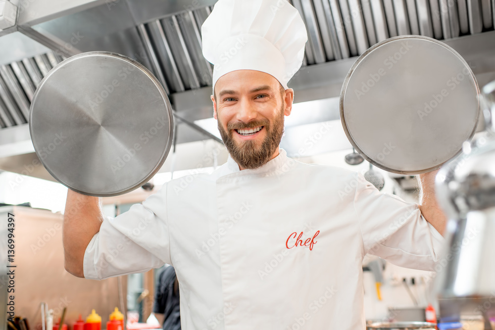 Crazy chef cook holding pan covers at the restaurant kitchen