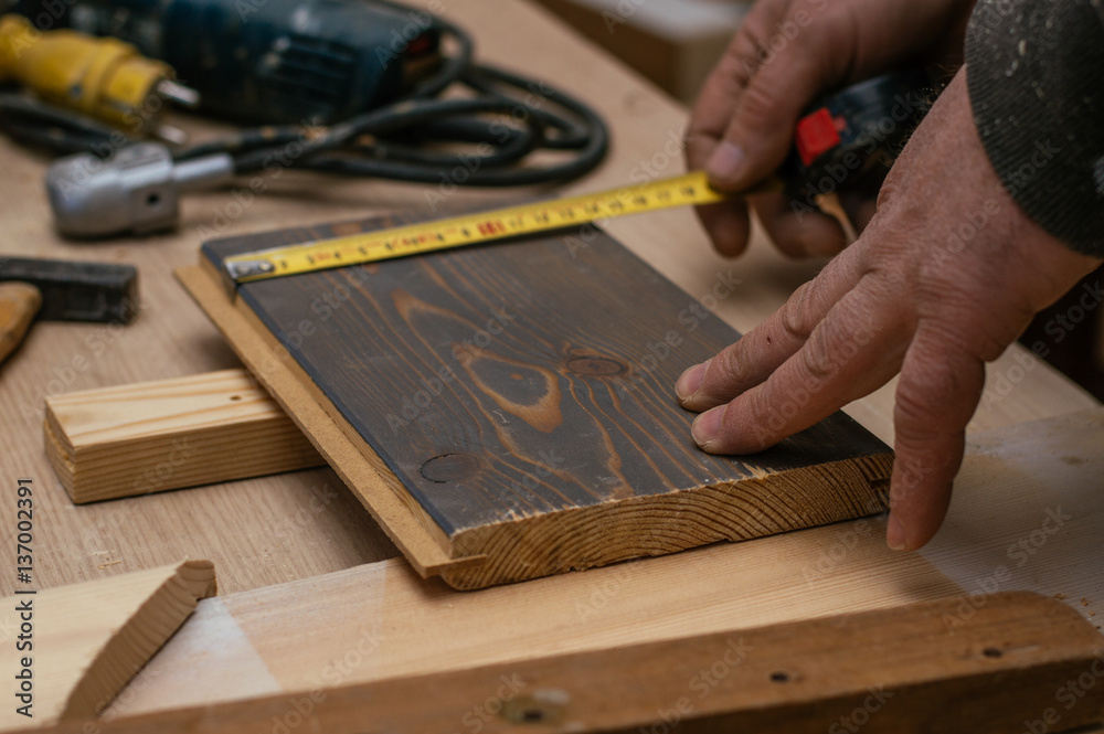 Craftsman measuring wooden plank with ruler