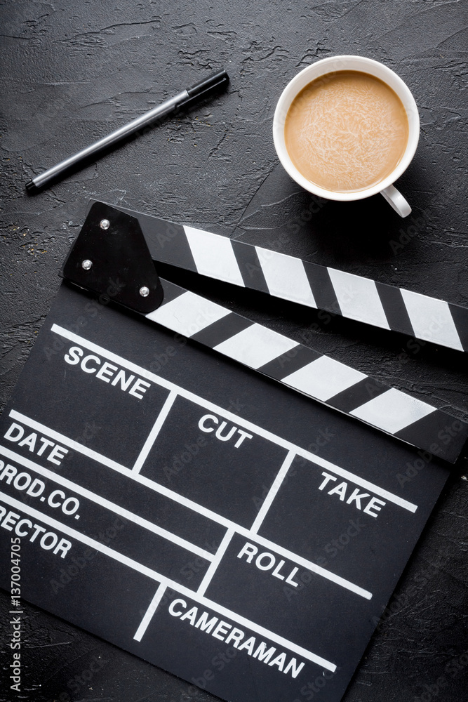 Screenwriter desktop with movie clapper board dark background top view