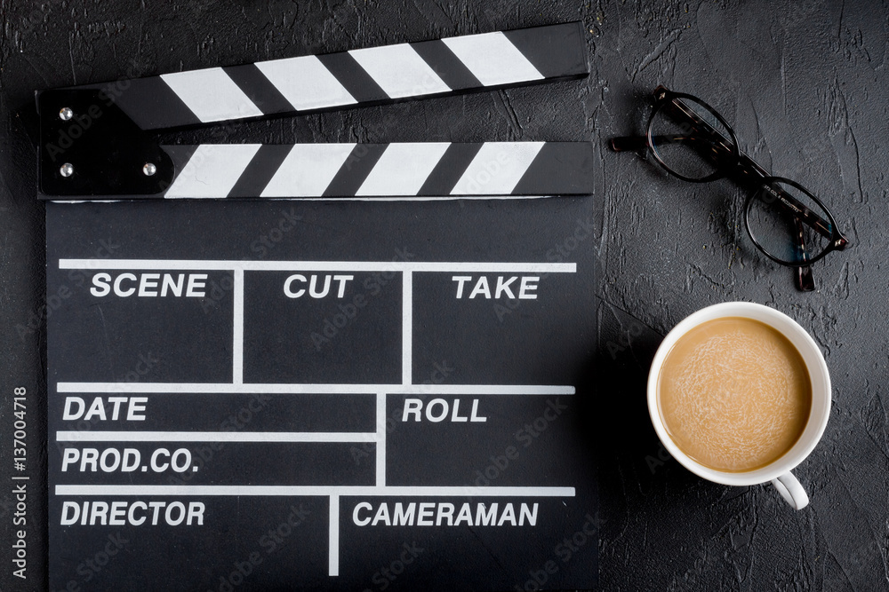 Screenwriter desktop with movie clapper board dark background top view