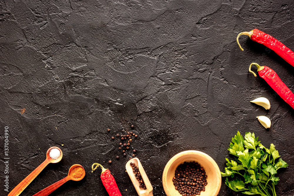 spices in wooden spoon on dark background top view