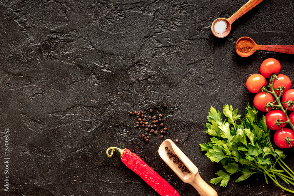 spices in wooden spoon on dark background top view