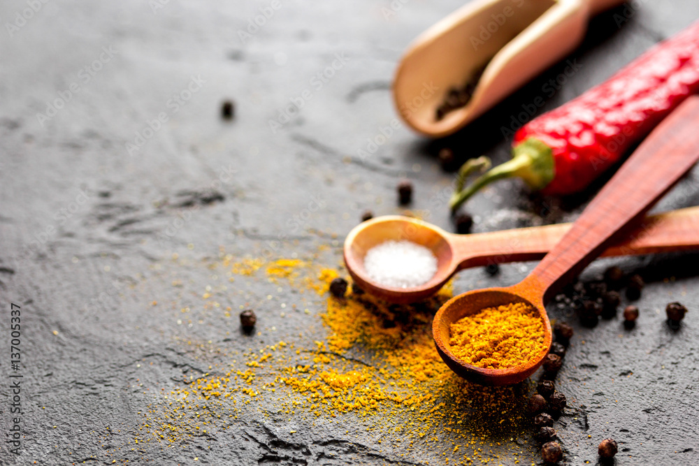 spices in wooden spoon on dark background