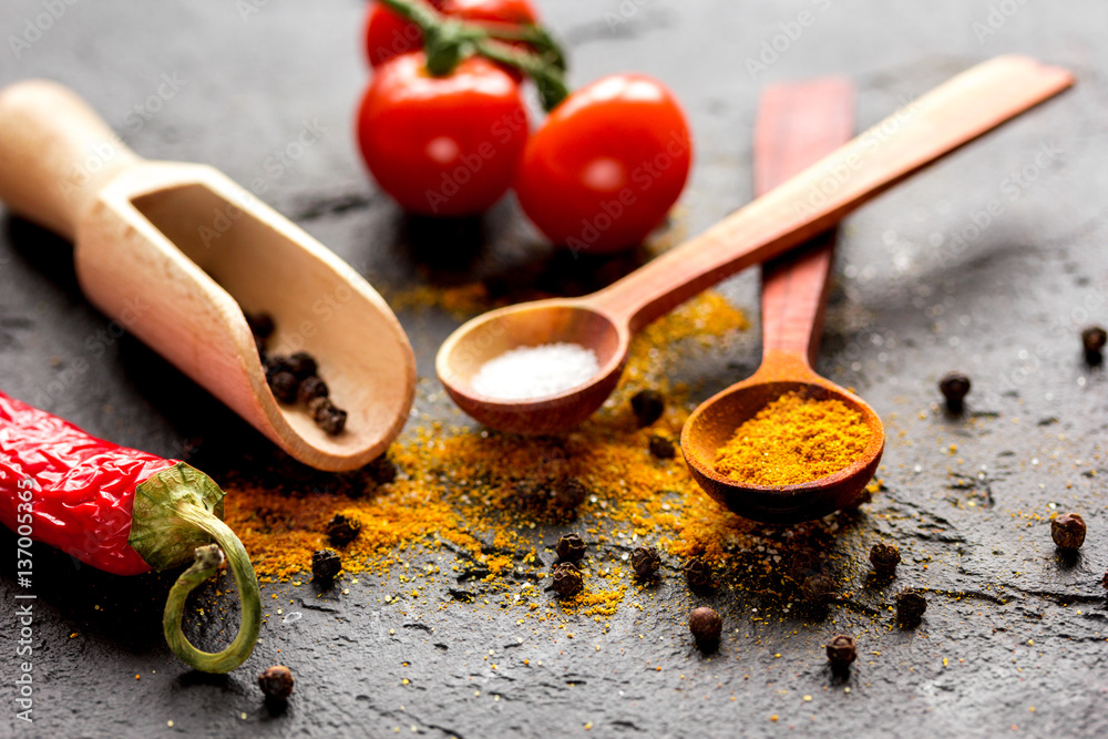 spices in wooden spoon on dark background