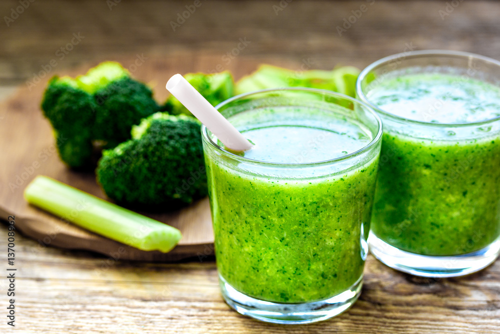 Green vegetable smoothie in glass at wooden background