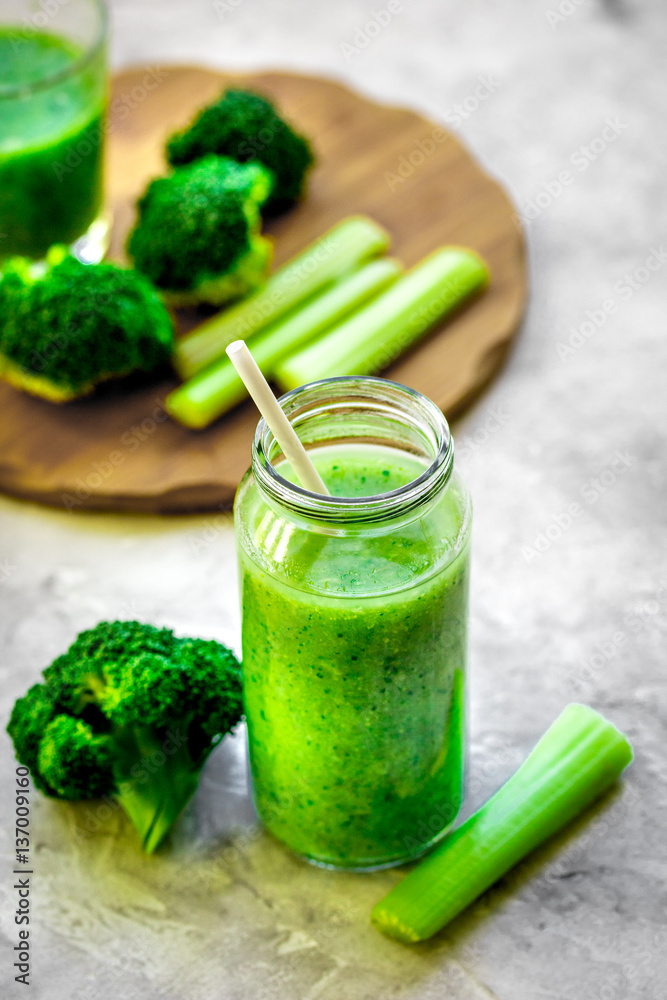 Green vegetable smoothie in glass at gray background