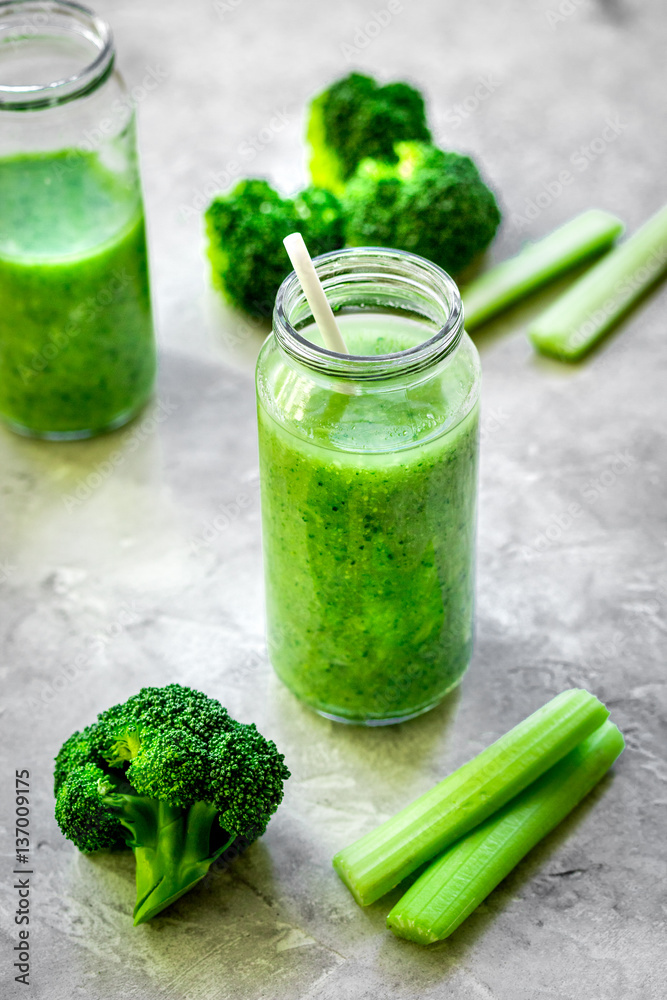 Green vegetable smoothie in glass at gray background