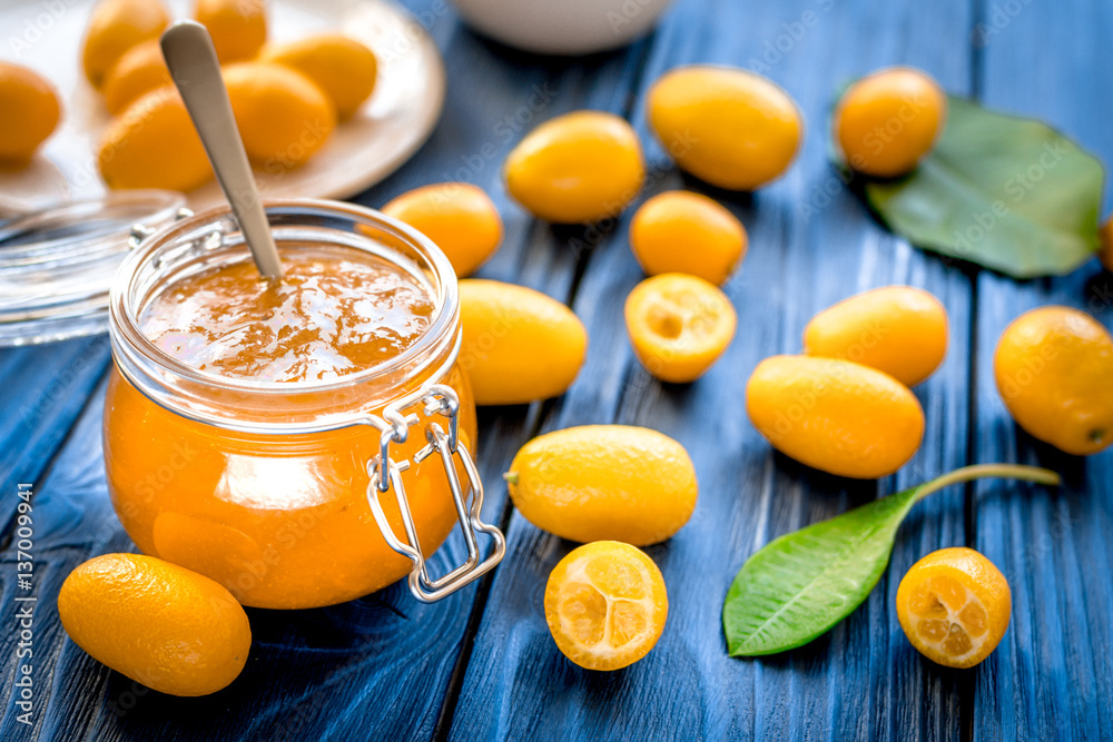 kumquat on plate and jam in jar at wooden table