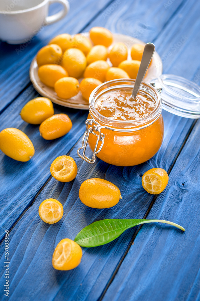 kumquat on plate and jam in jar at wooden table