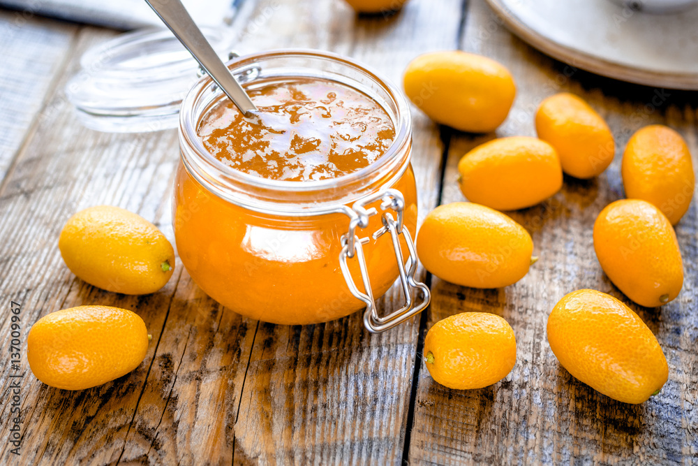 kumquat on plate and jam in jar at wooden table