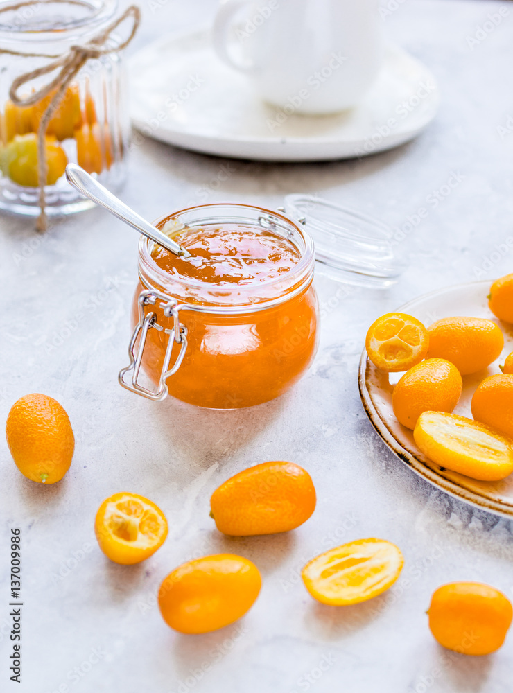 kumquat on plate and jam in jar at gray background