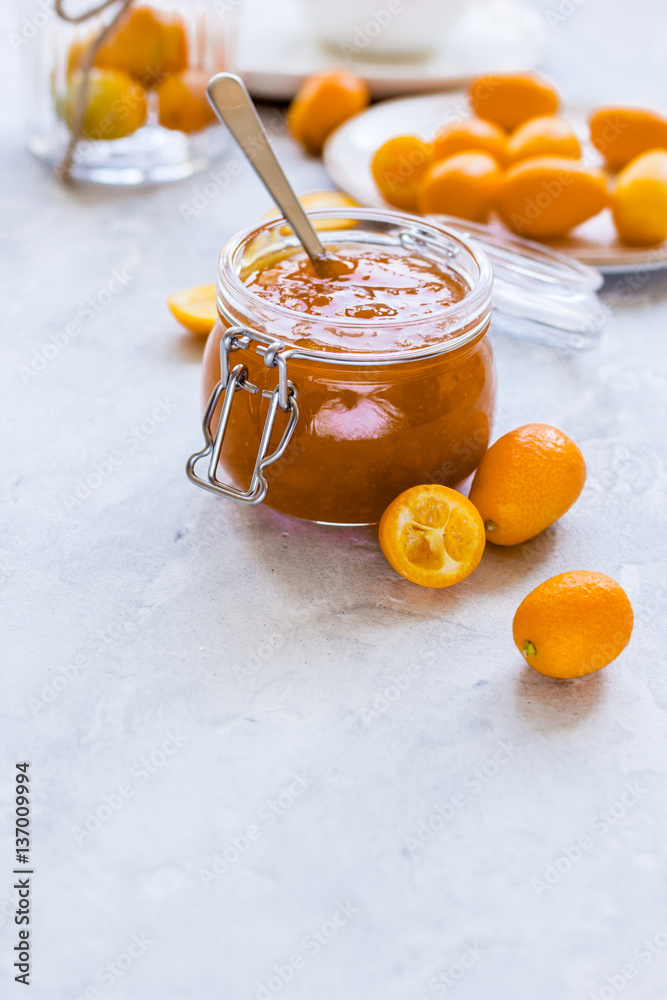 kumquat on plate and jam in jar at gray background