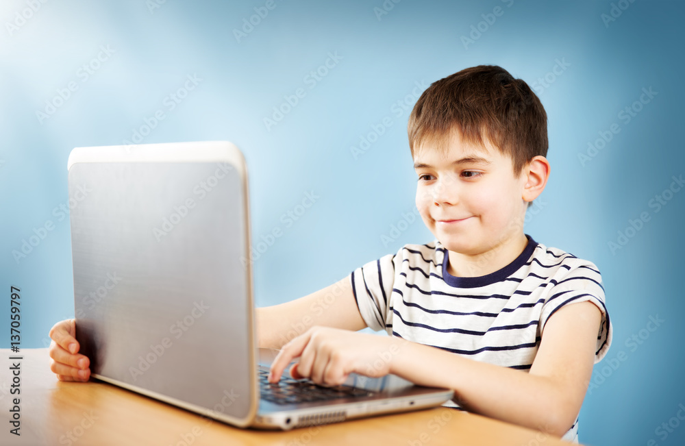 seven years old child sitting with a laptop at table and typing