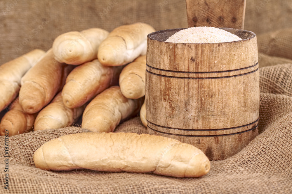 Vintage small wooden bucket with breadcrumbs and blurry bread rolls in the background