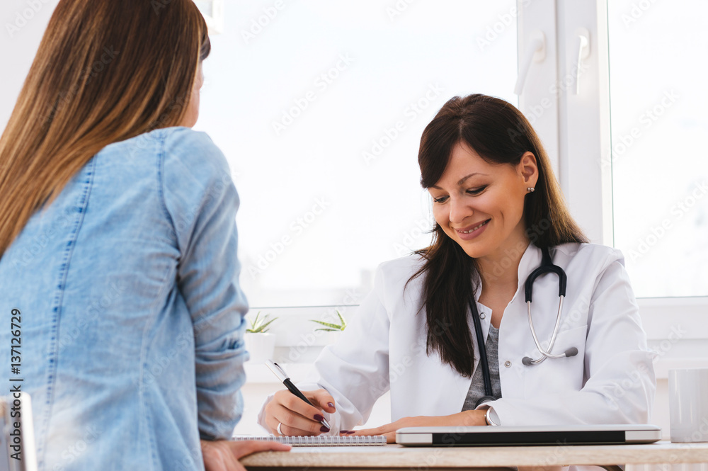 Female doctor writing prescription to patient