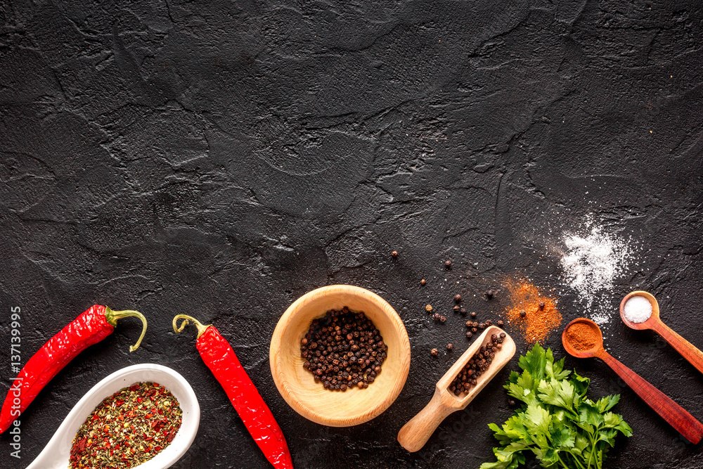 spices in wooden spoon on dark background top view