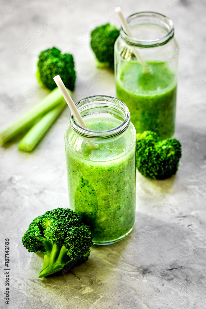 Green vegetable smoothie in glass at gray background