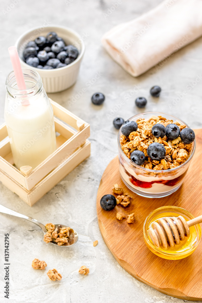 Morning granola with yogurt, honey and berries on white table