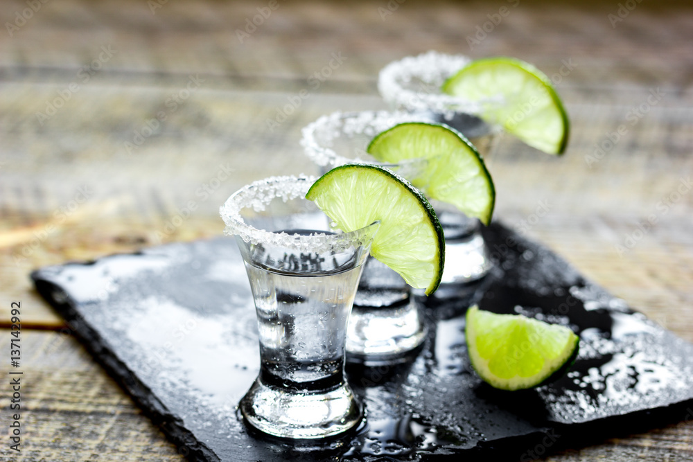 Party in bar with tequila, salt and lime on wooden table