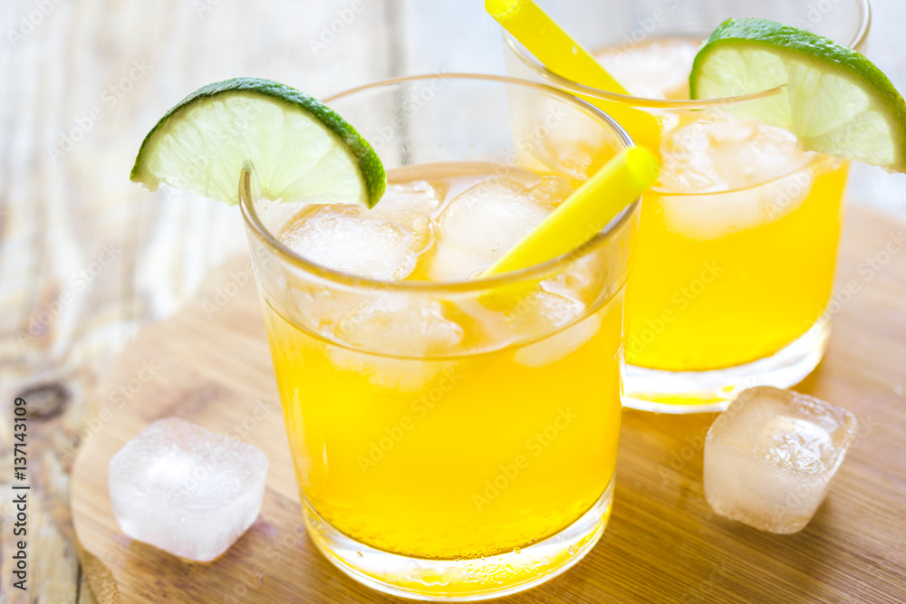 Alcohol orange cocktails with lime and ice on wooden background