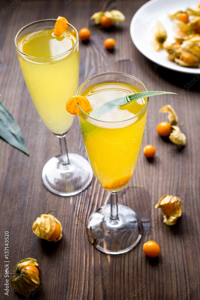 cocktail with physalis in glass on wooden background