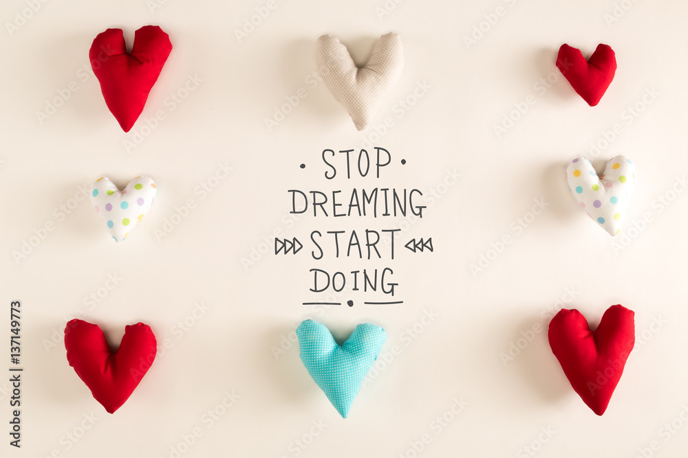 Stop Dreaming Start Doing message with blue heart cushions on a white paper background