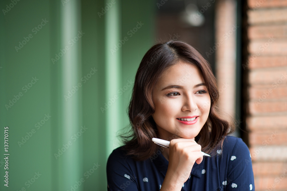 年轻漂亮的女人在靠近窗户的咖啡馆里，一边思考一边写着什么。